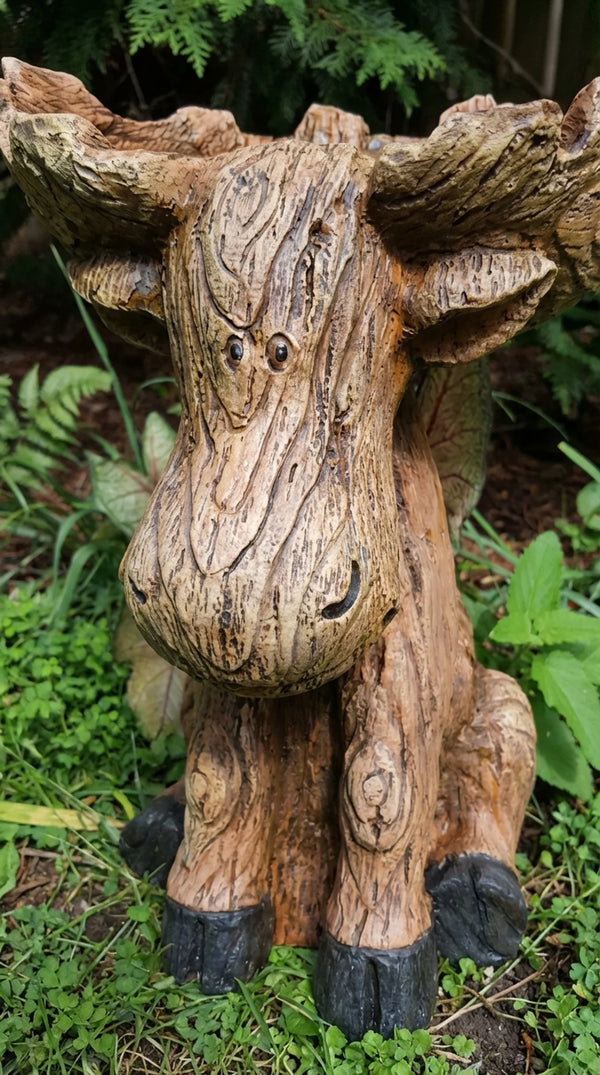 Wooden moose sculpture in a natural setting with greenery