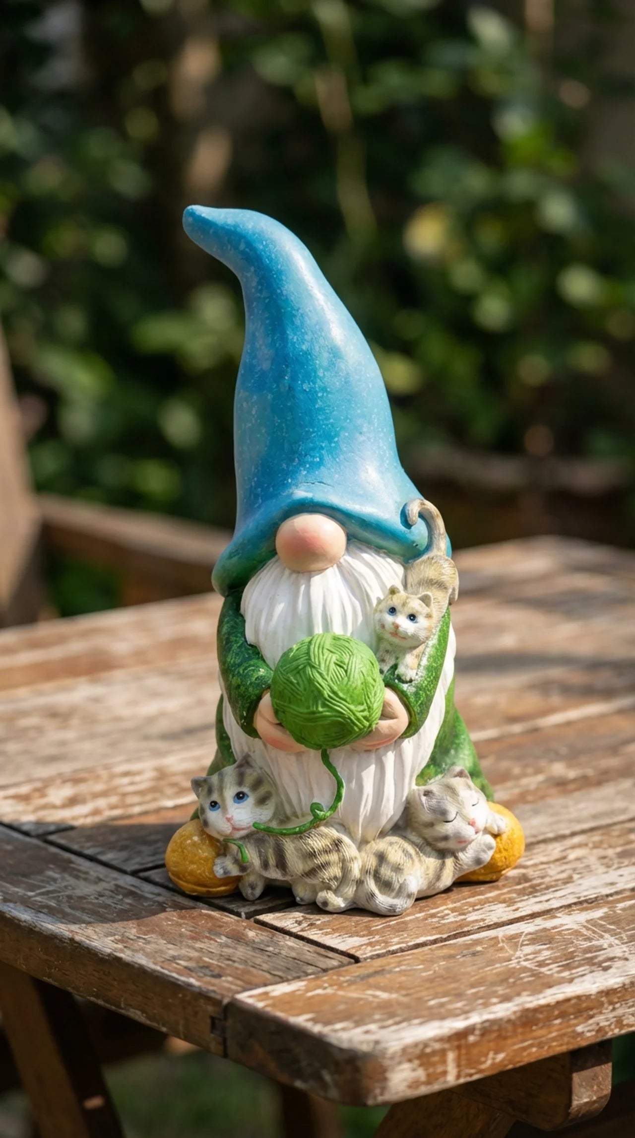 Resin gnome with cats statue placed in garden border, full figure visible, natural daylight, outdoors