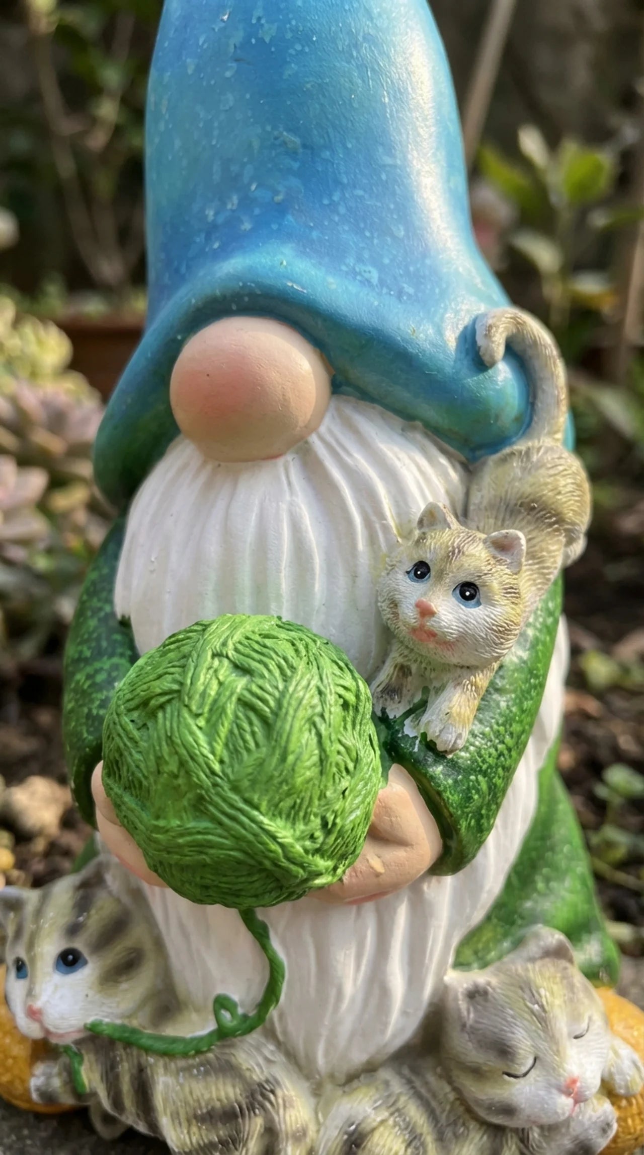lose-up of Barnaby ornament showing hand-painted cat detail, green yarn ball, blue hat with solar panel, and white beard.