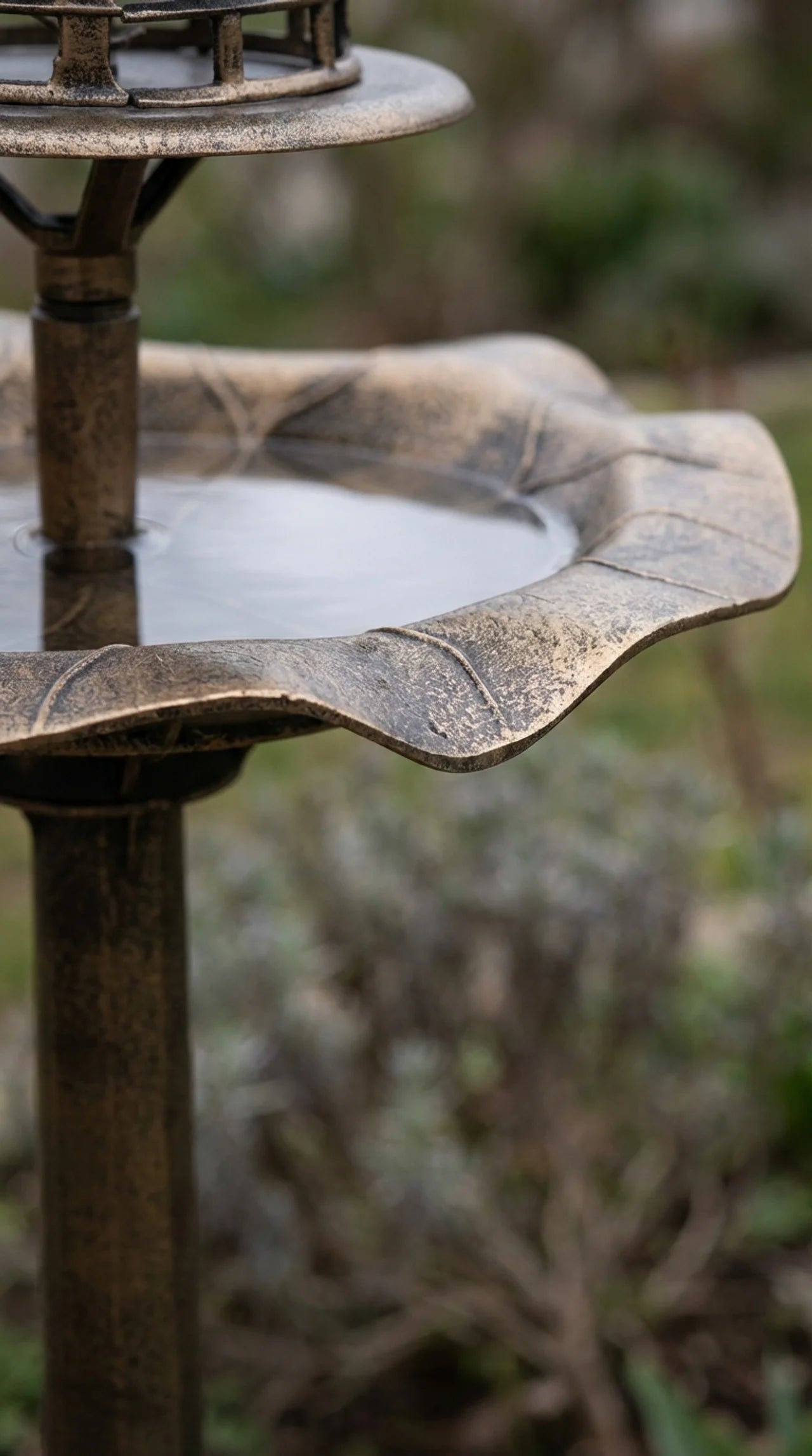 Close-up of aged bronze effect finish and leaf-shaped basin detail on decorative garden bird bath stand