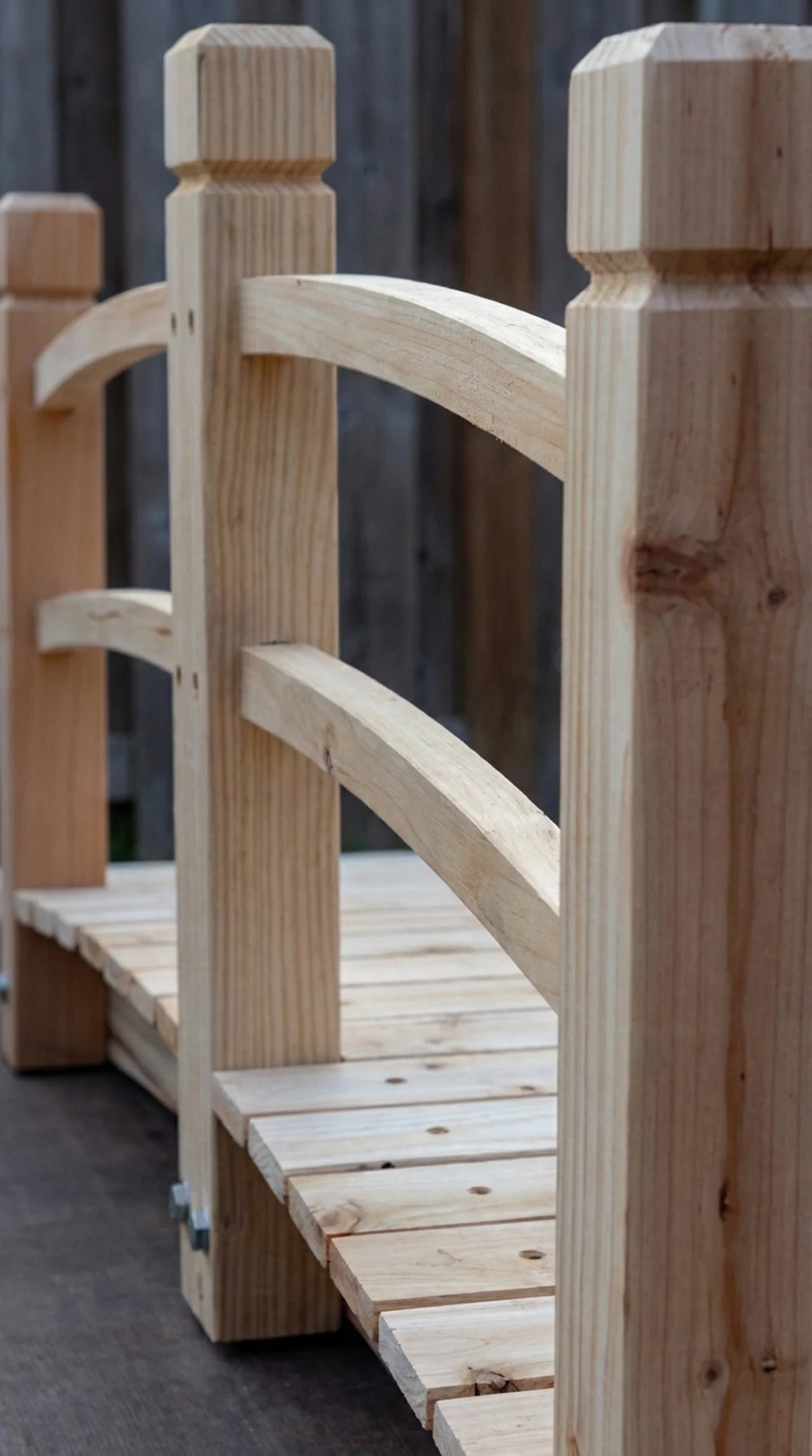 Close-up of slatted fir deck boards and curved timber handrail detail on wooden garden footbridge