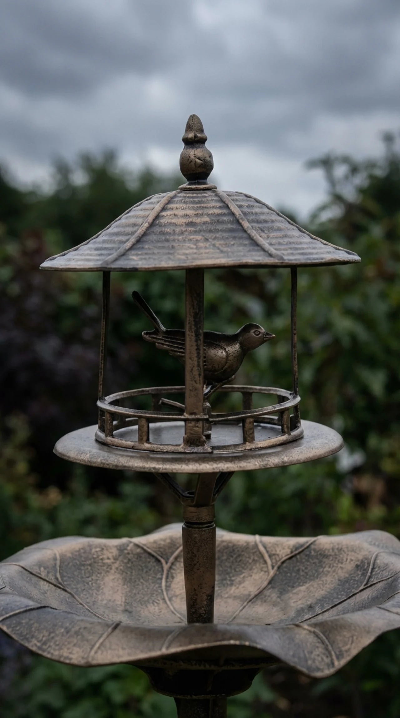 Close-up of aged bronze effect finish and leaf-shaped basin detail on decorative garden bird bath stand
