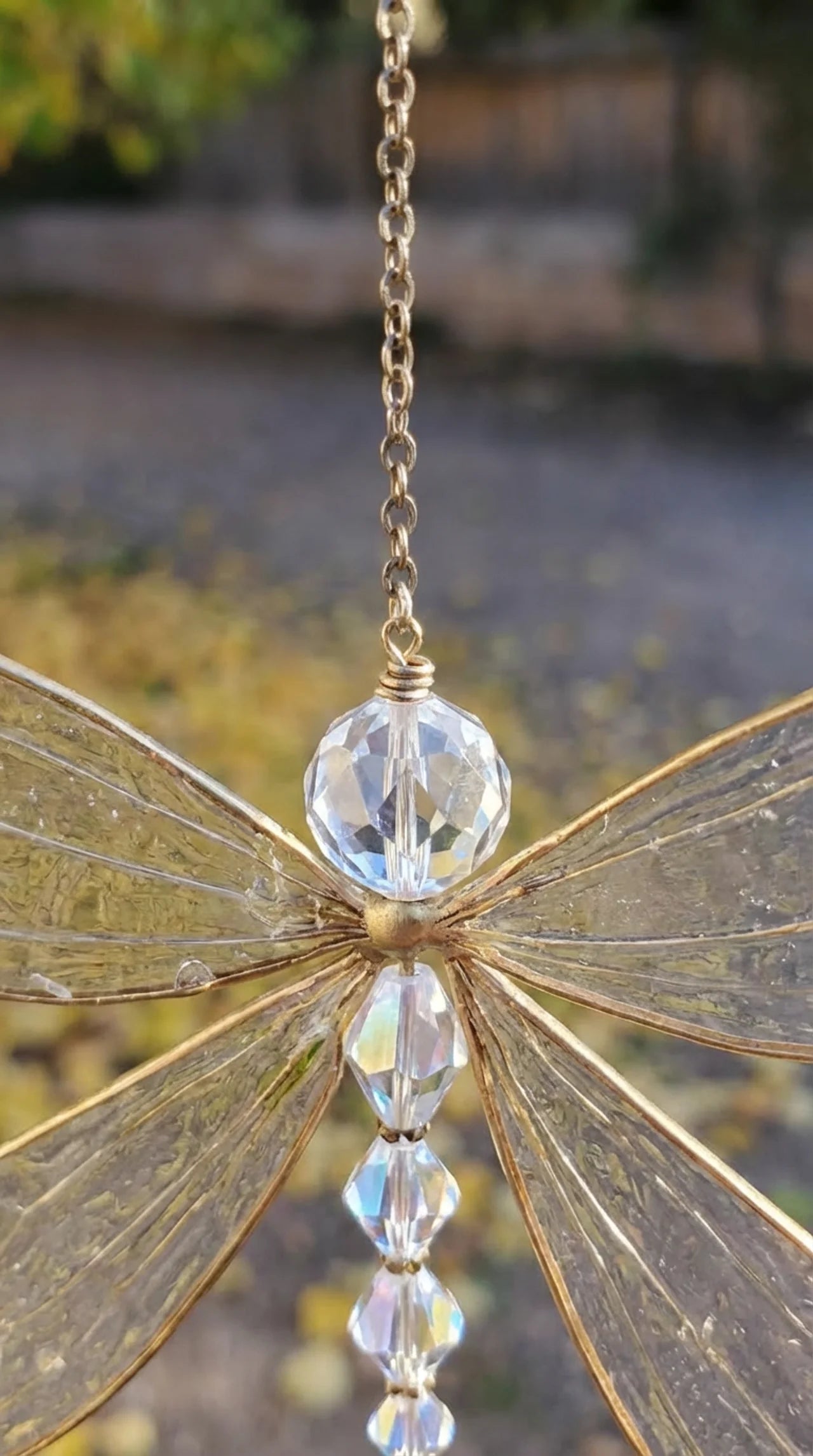 Close-up of electroplated dragonfly wing detail and faceted crystal pendant on hanging suncatcher