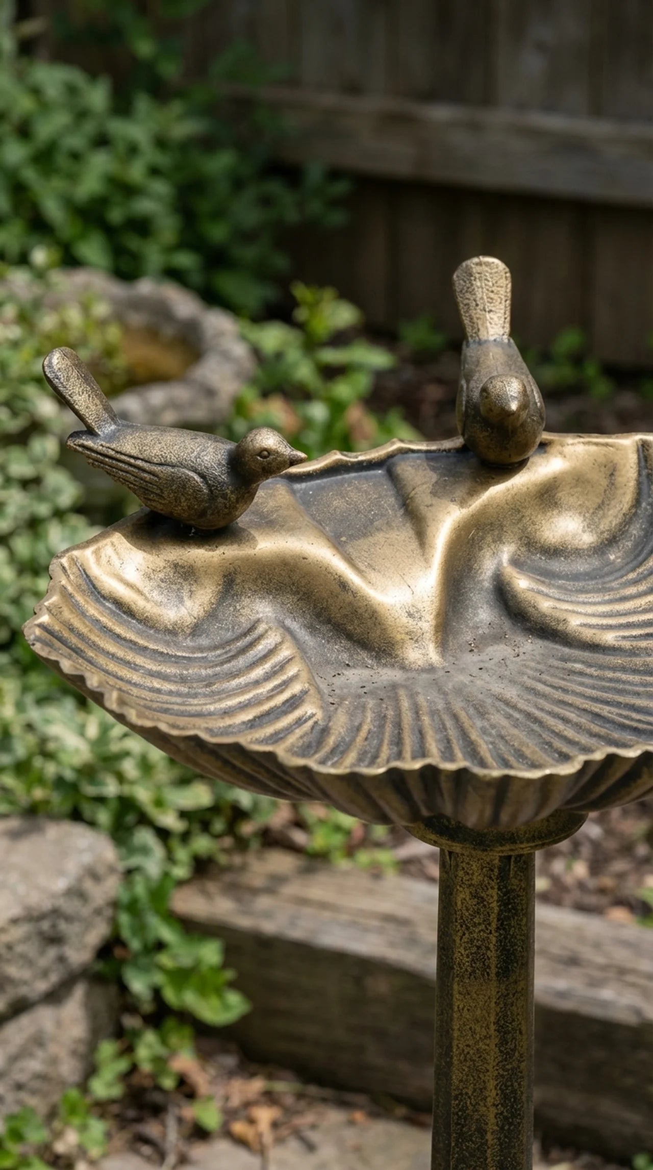Close-up of hantique bronze finish and bird figure detail on decorative bird bath pedestal