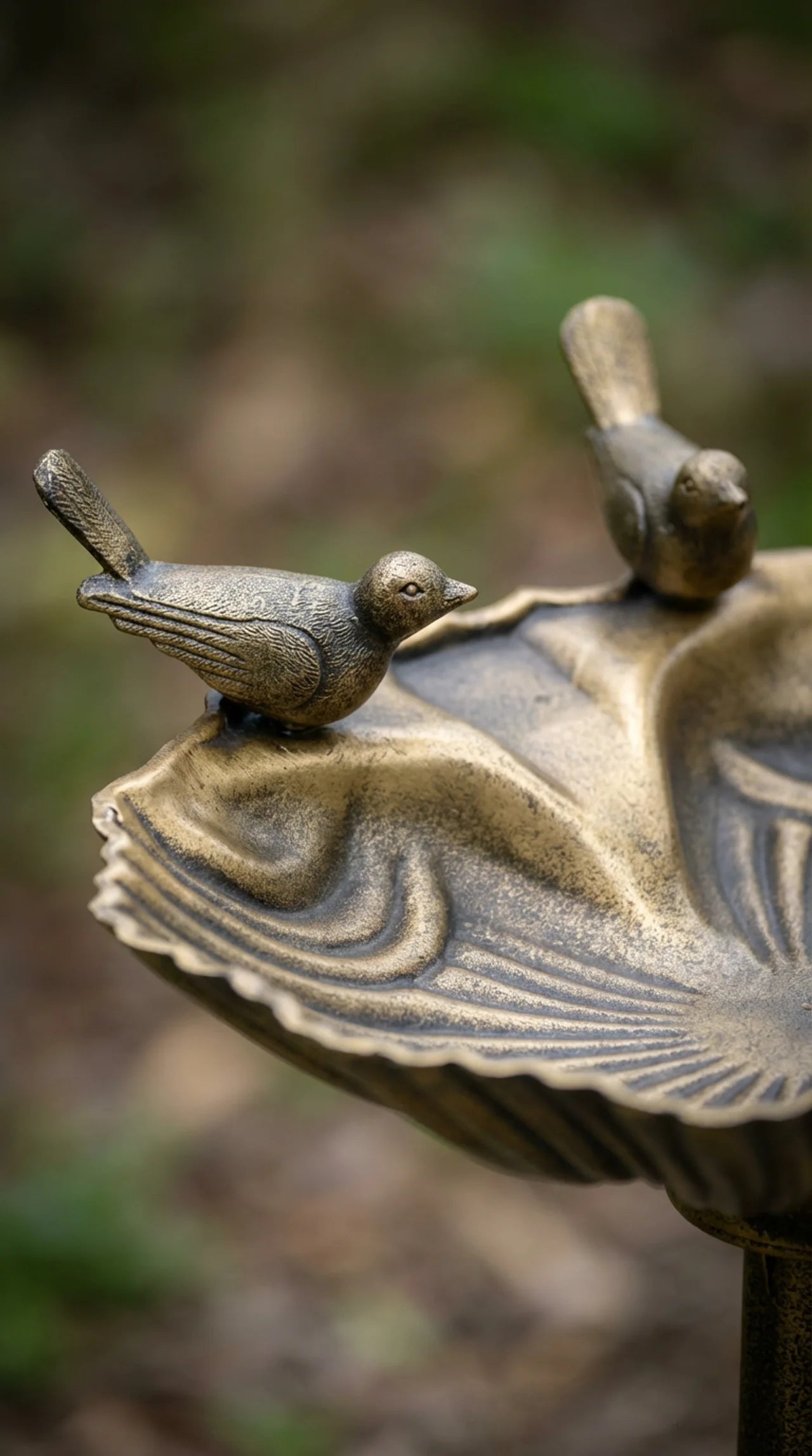 Close-up of hand-painted antique bronze finish and bird figure detail on decorative bird bath pedestal
