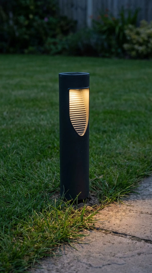 Black outdoor lamp post on grass with a warm glow