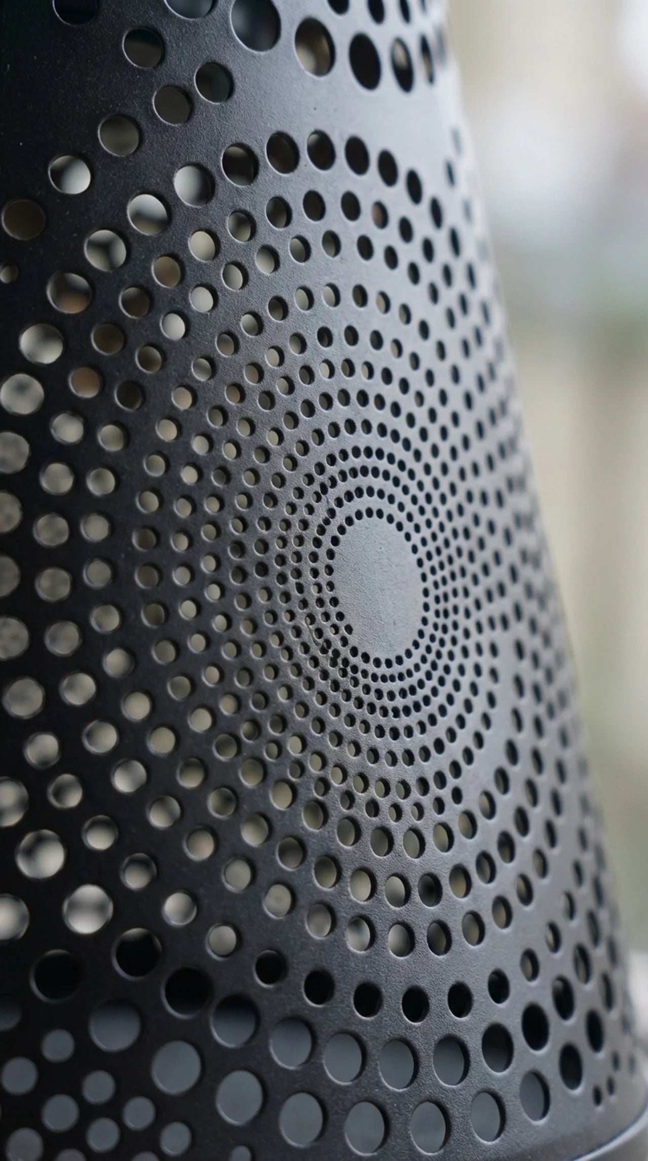Close-up of cut floral filigree pattern on metal solar hanging lantern glowing warm at night